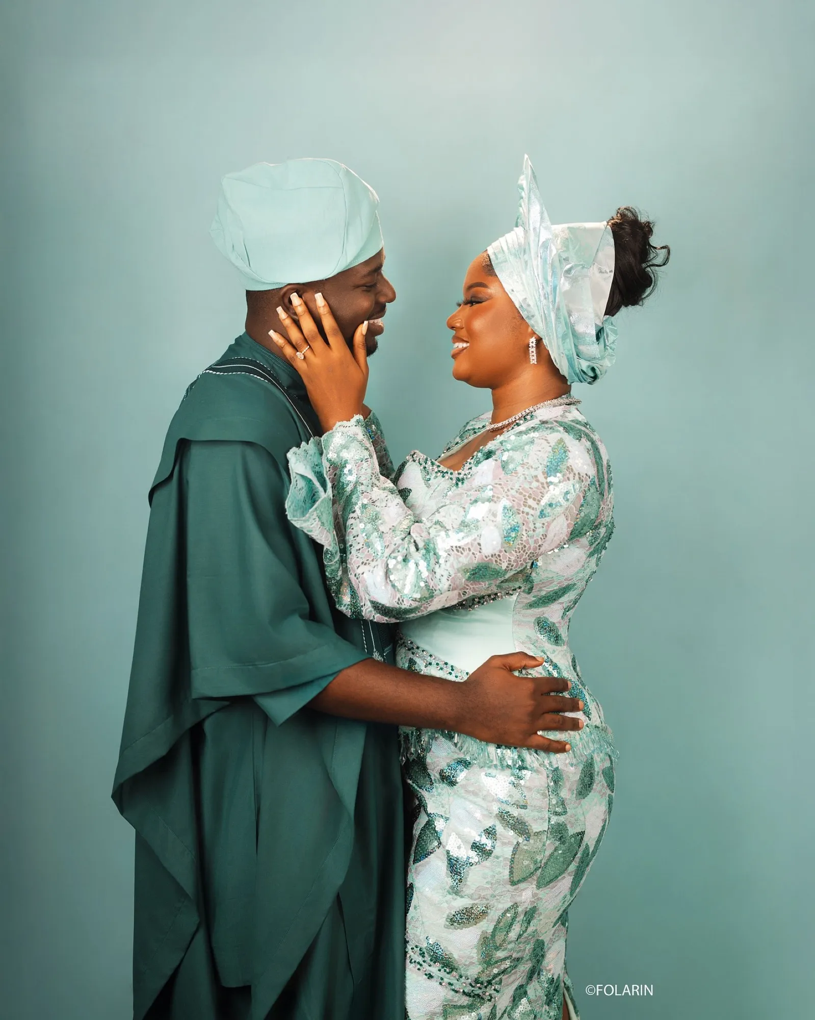 Toluwalope and Oluwaseyi in teal aso-oke, forehead to forehead