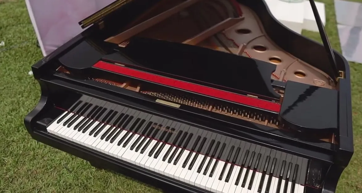 A black grand piano set beside the altar on the lawn