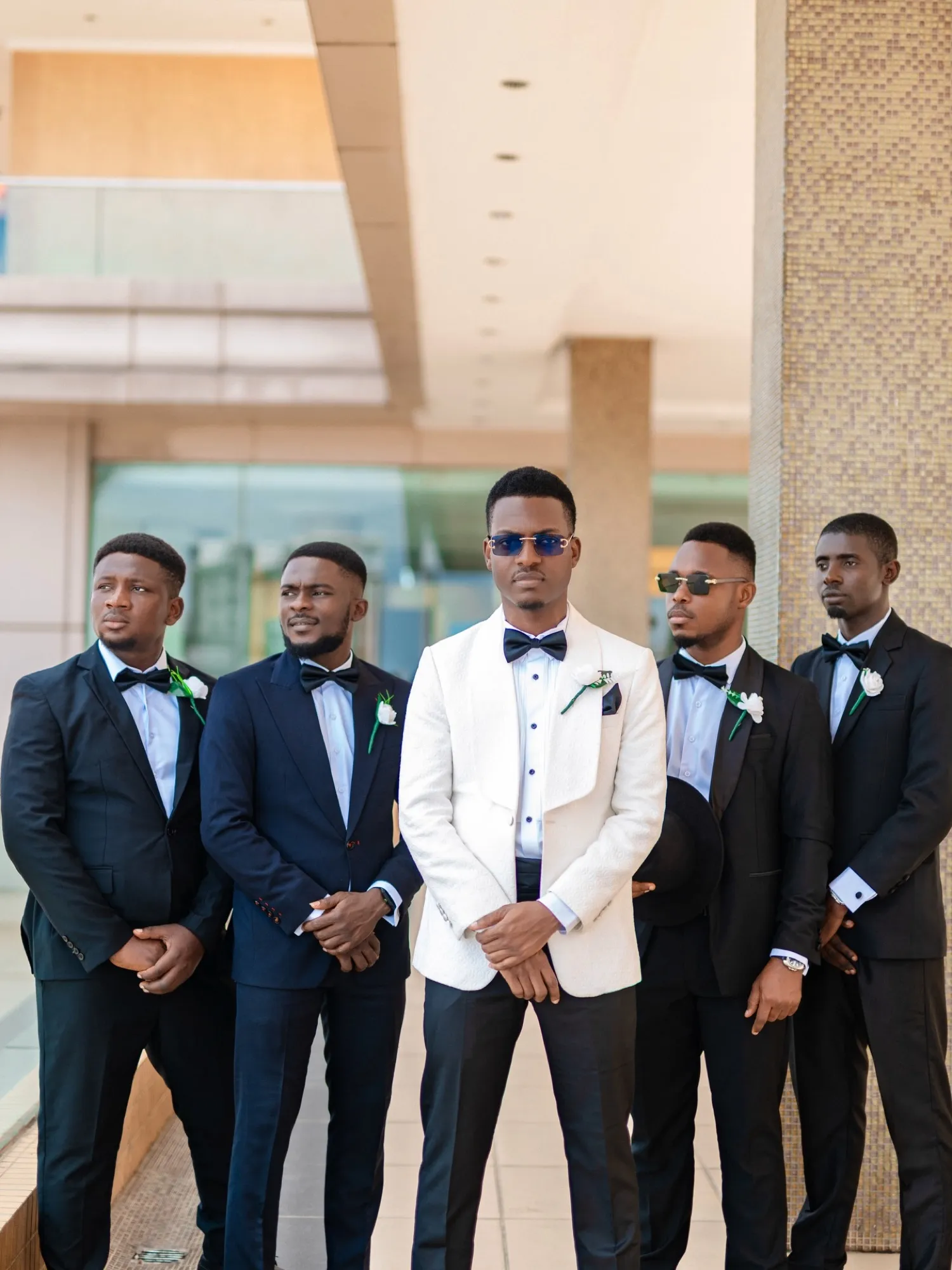 Groom in a white tuxedo with groomsmen in black