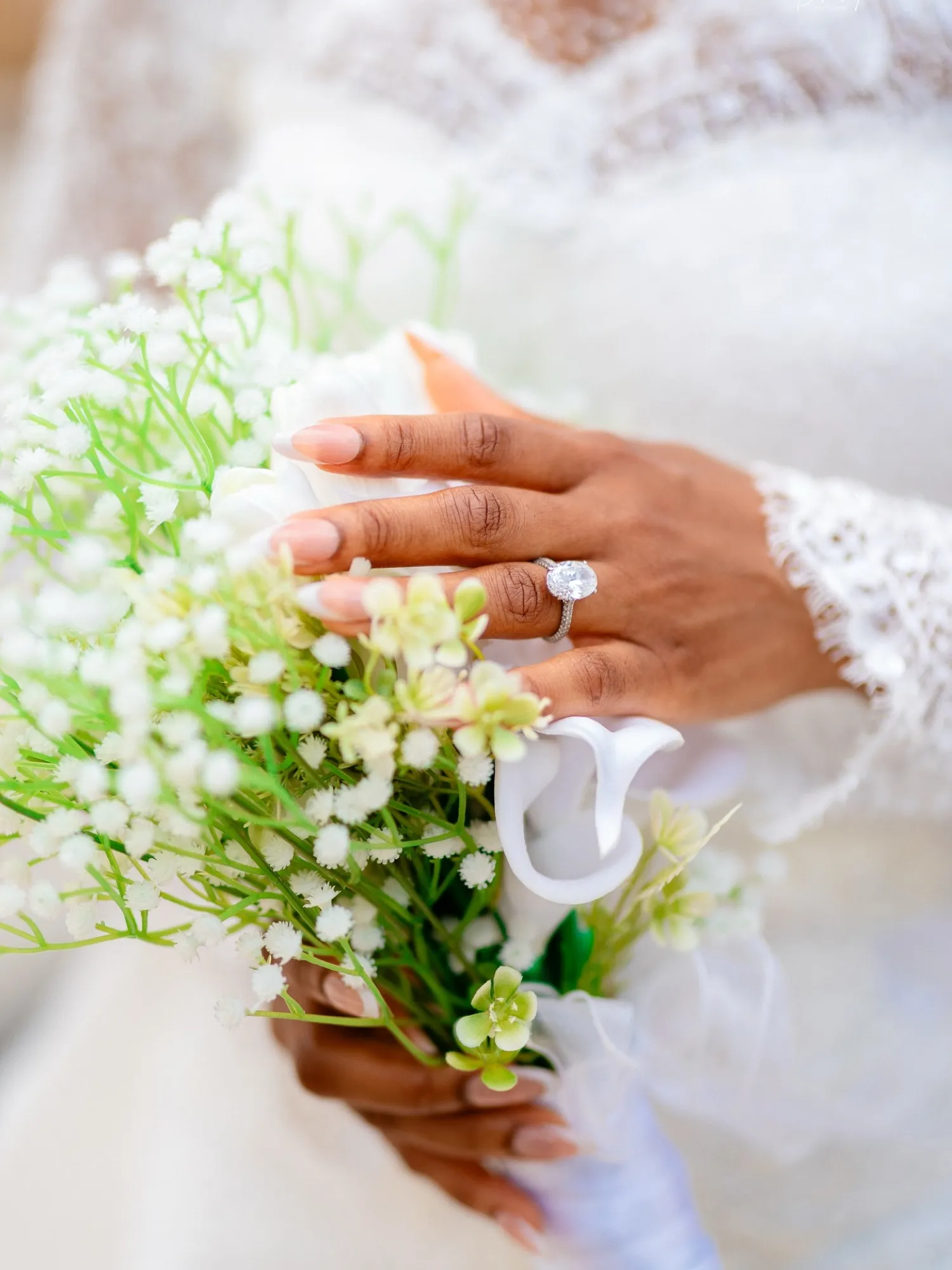 Bride's hand with a diamond ring and baby's breath bouquet