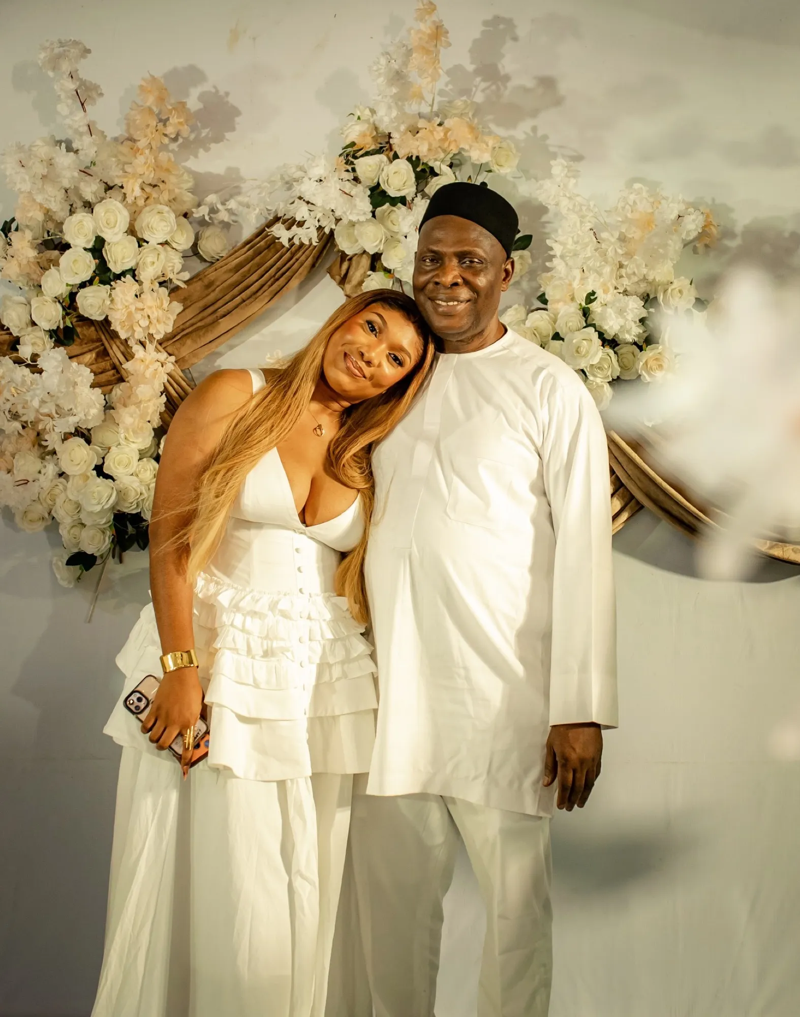 Hosts in white in front of a floral arch