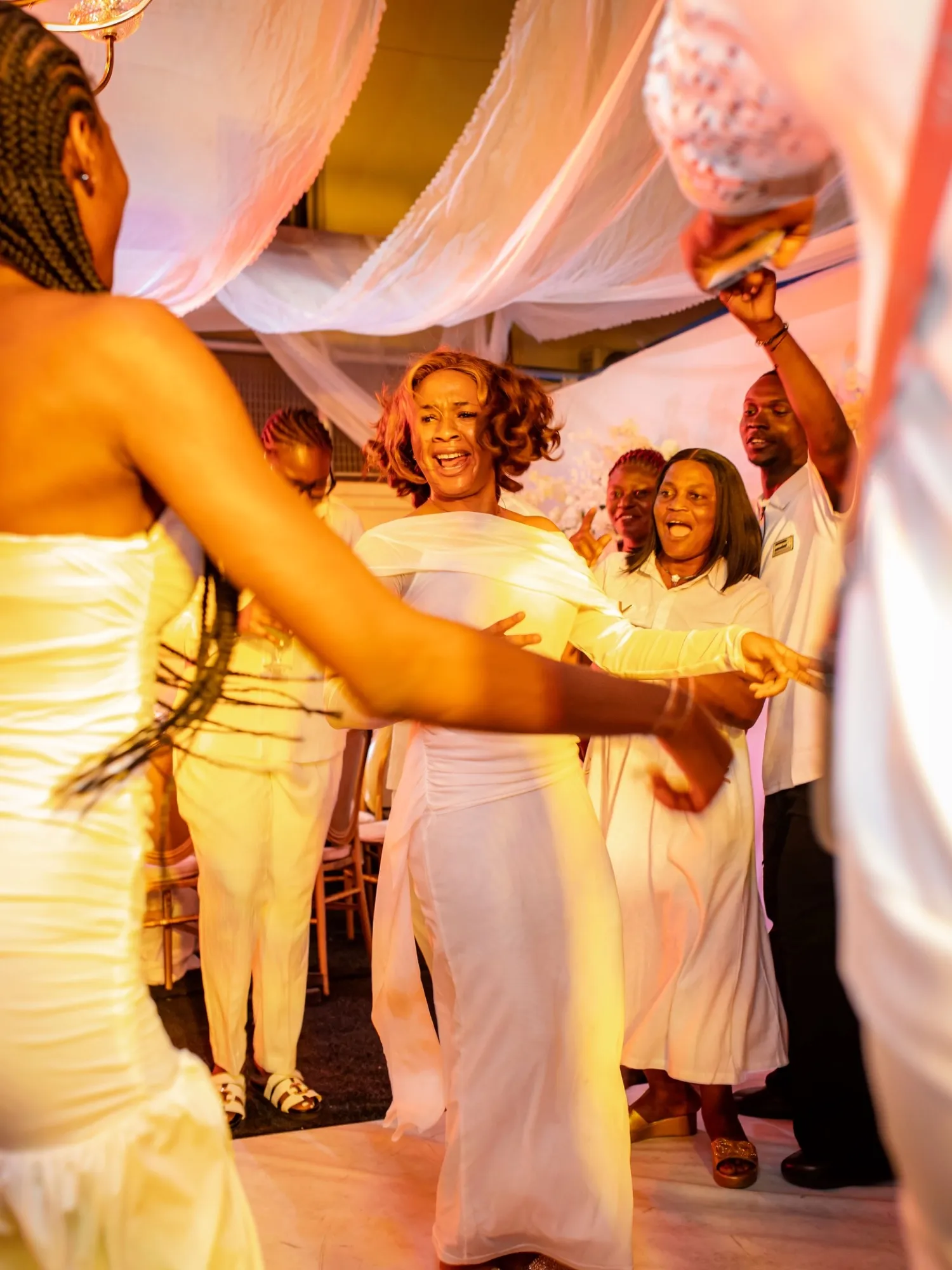 Guests in white dancing under draped fabric