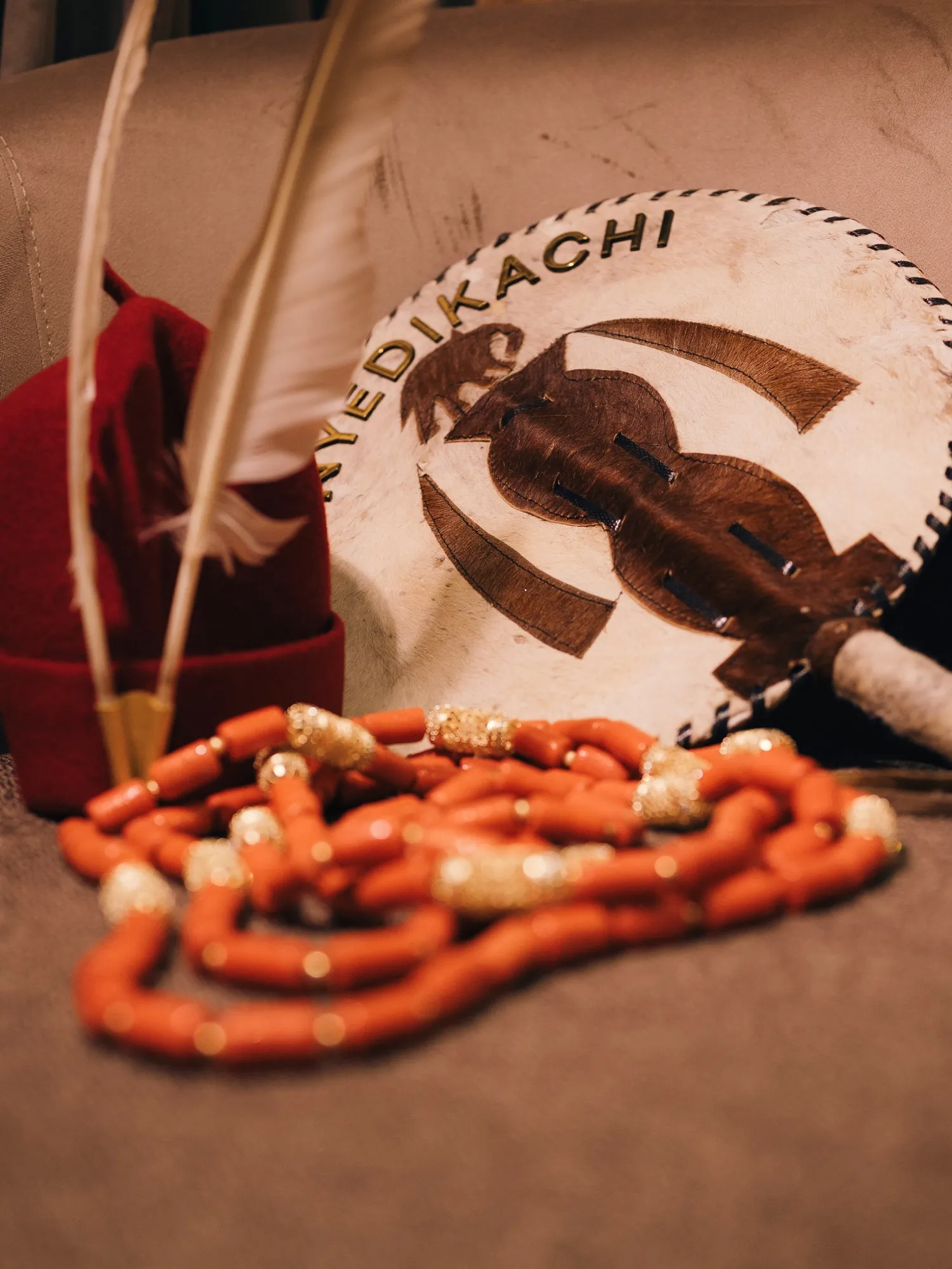 Coral beads laid out beside a carved Onyedikachi fan