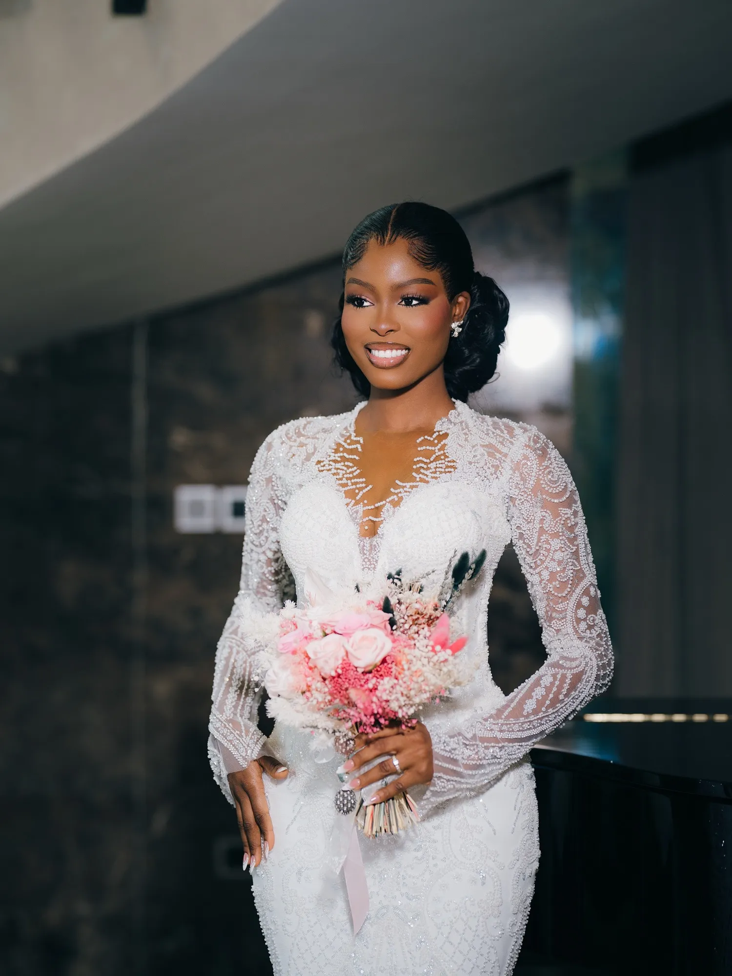 Bride holding a pink bouquet beside a curved staircase