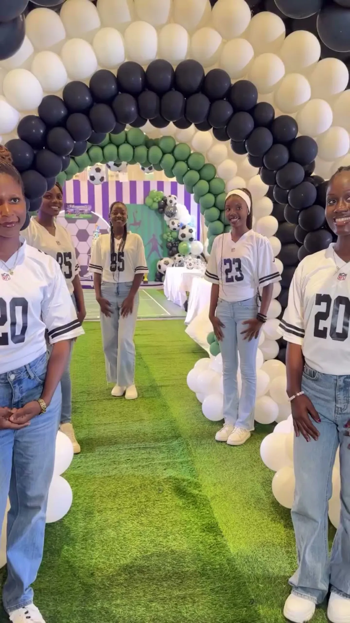 Guests in football jerseys walking through a black and white balloon tunnel